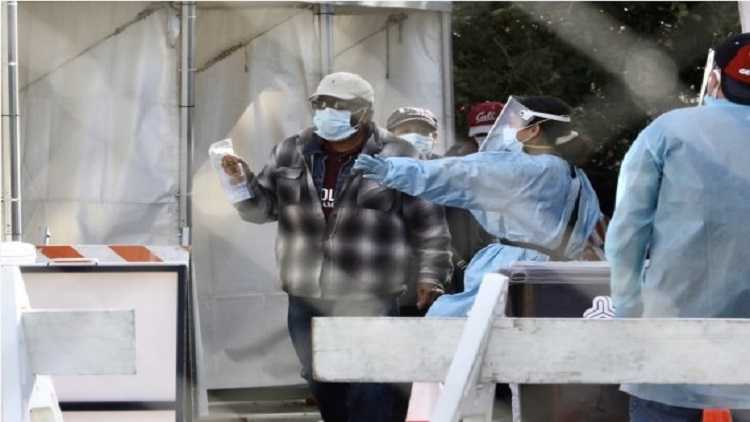 A healthcare worker helps people check in for COVID-19.