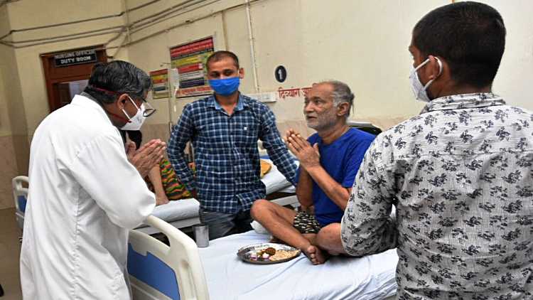 Medical Superintendent Prof. K. K. Gupta greets a COVID patient with black fungus disease, at Sir Sunderlal Hospital in Varanasi on Friday