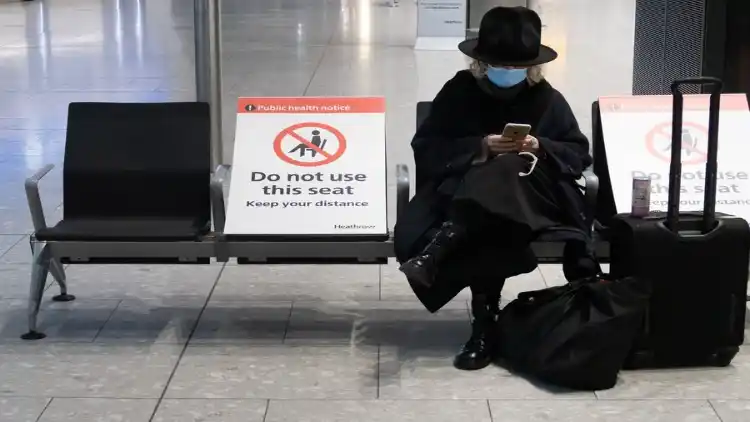 A woman waits in the arrivals hall at Heathrow Airport in London