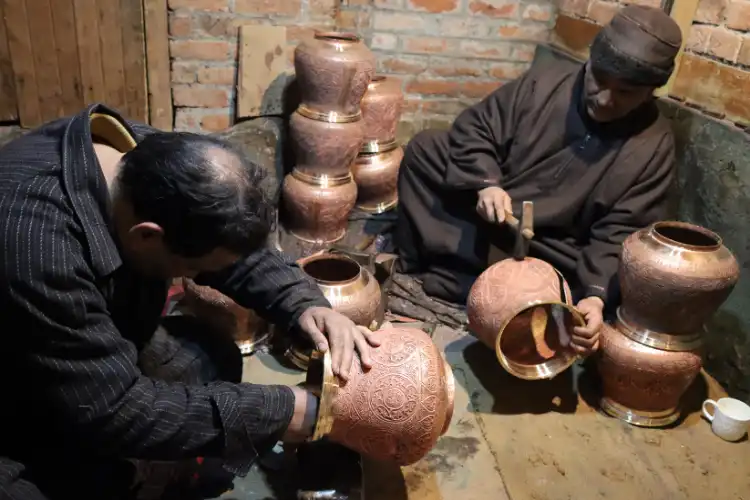 Artisans making carved copper vessels in Srinagar