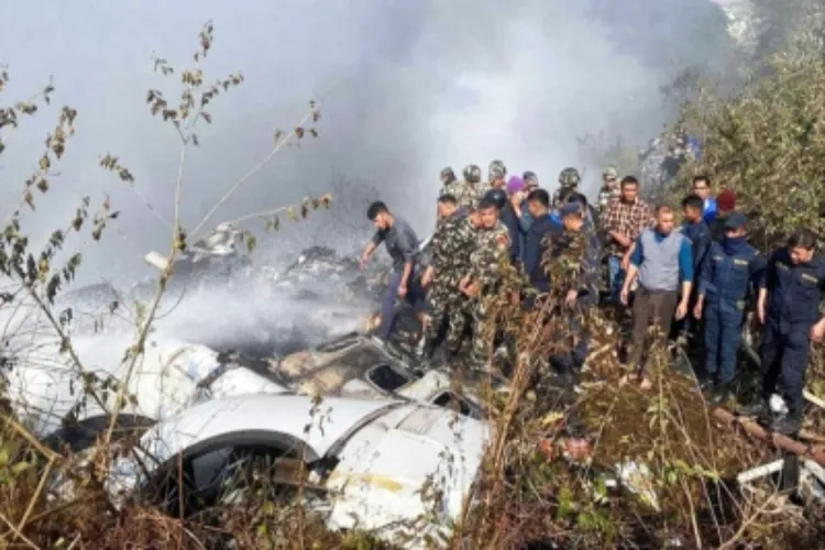 Locals watch the wreckage of a passenger plane in Pokhara, Nepal on Sunday