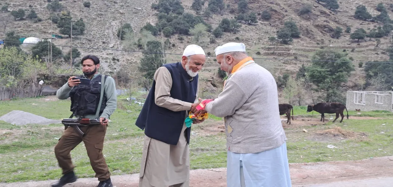 Sarpanch Abdul Rashid khokar greeting Ravinder Pandita, leader of the Save Sharda Movement in Teetwal, as a security personnel clicks pictures (Courtesy Twitter of Ravinder Pandita) 