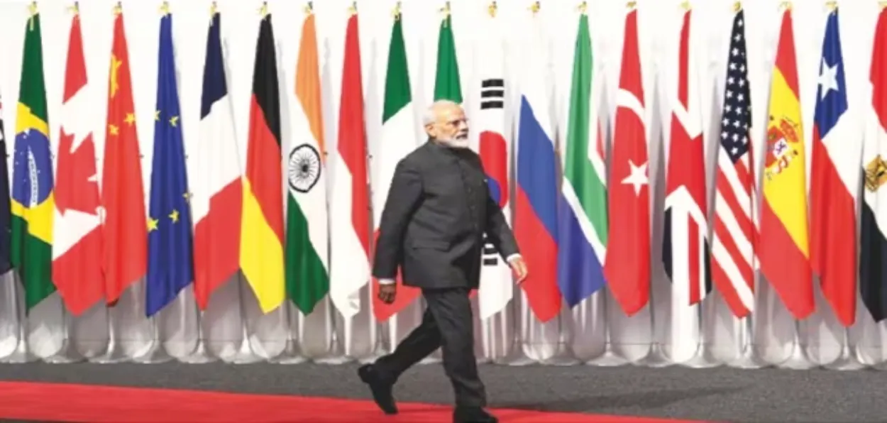 Prime Minister Narendra Modi walking past the flags of different countries at a global conference