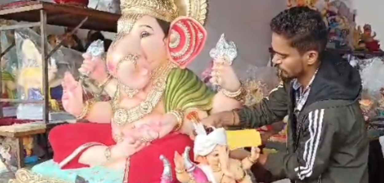 Aslam trying Rakhi to the idol of Ganesha