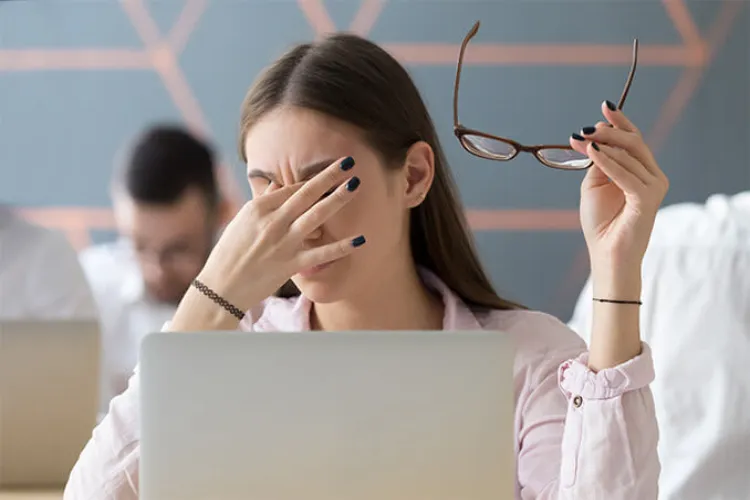 A woman struggling with eye strain caused due to prolonged computer screen exposure
