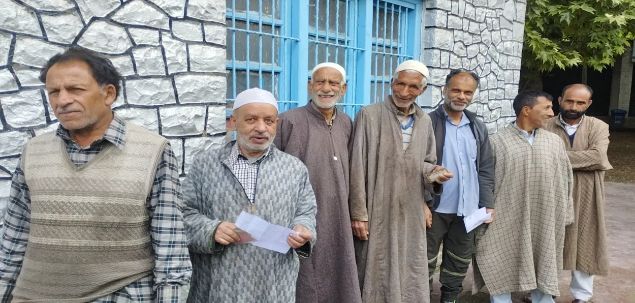 Kashmiri voters in traditional Kashmiri dress Phiren waiting for their turn to cast their vote 