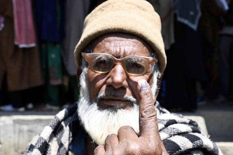 A Kashmiri shows his ink mark after voting in Ganderbal