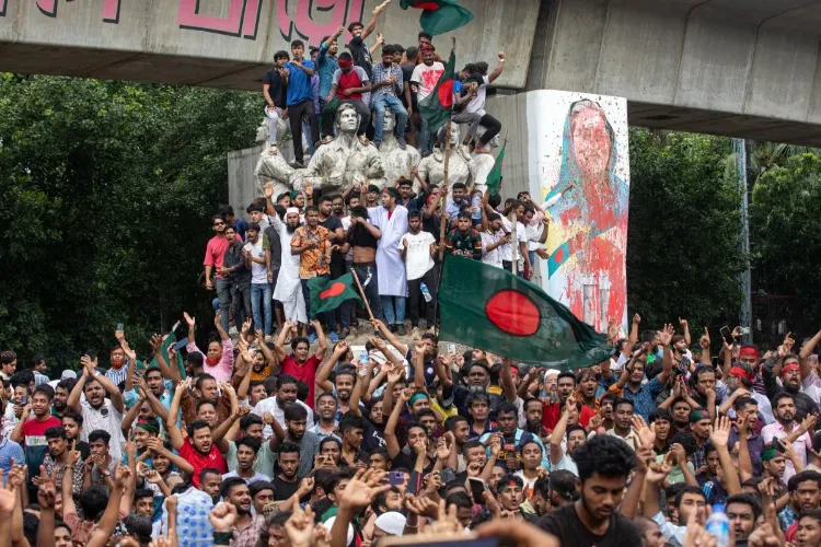 Protesters climb a public monument as they celebrate the news of Prime Minister Sheikh Hasina's resignation