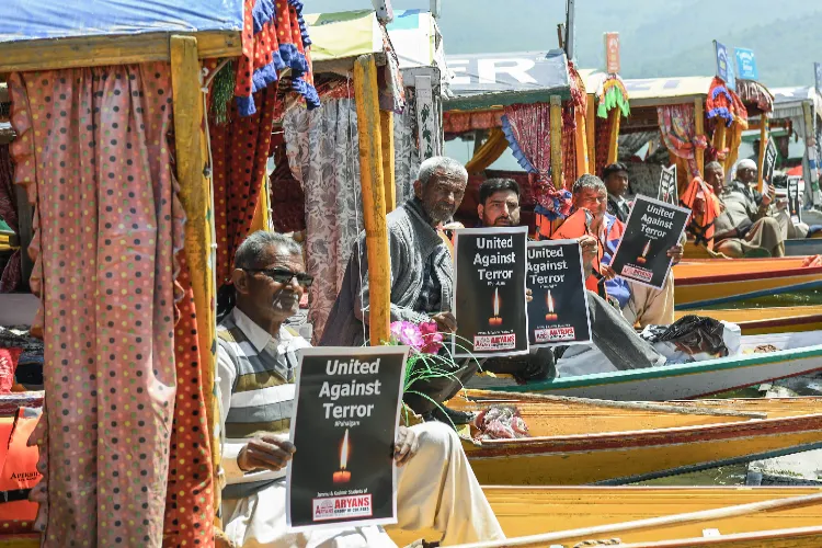 Boatmen holding placards with 'United Against Terror' written on them, protest against the Pahalgam terror attack, at Dal Lake in Srinagar on Thursday.