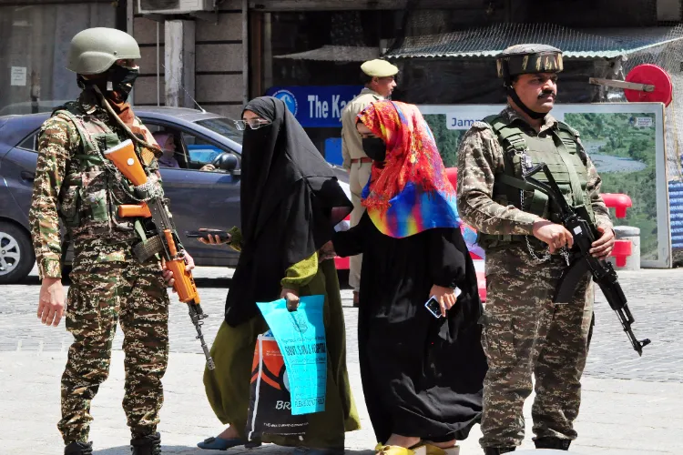 Women pass on a road as Security personnel stand guard at Lal Chowk after security heightens following the Pahalgam terror attack, in Srinagar on Thursday. 