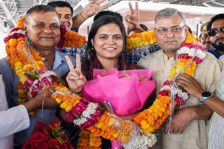 UPSC 2025 topper Shakti Dubey who has secured All India Rank 1 in the Civil Services Examination poses for a picture with her father Devendra Kumar Dubey and uncle AK Dubey on her arrival, at Prayagraj Junction Railway Station in Prayagraj.