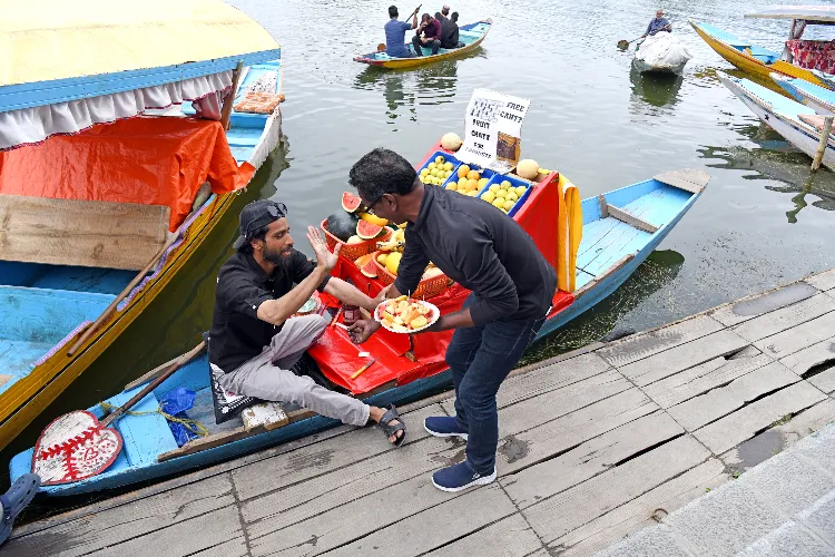 Fruit seller Hashim Ali sells free fruit chaat to a tourist on Dal lake following the Pahalgam terror attack, in Srinagar on Saturday. 