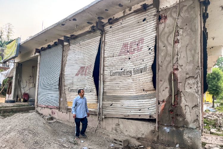 A civilian looks at damaged properties after heavy firing and shelling by Pakistan military overnight across the Line of Control and International Border