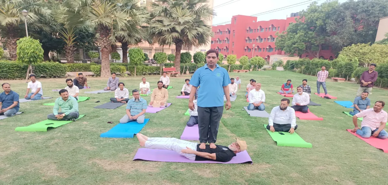 Dr Badrul Islam Kairanvi making a person stand on his abdomen during a Yoga practice session