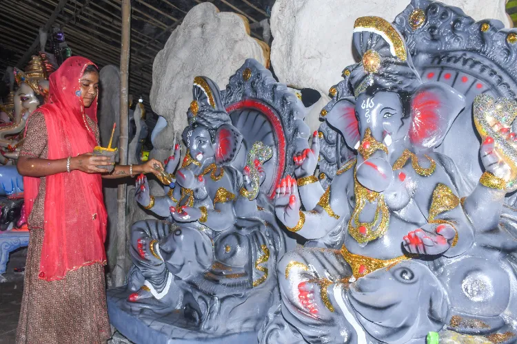 An artist gives final touches to idol of lord Ganesh