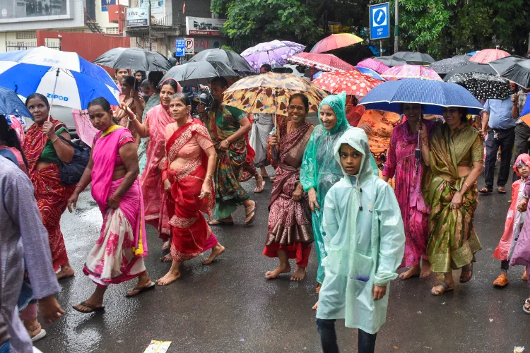 People protect themselves with umbrellas amid rainfall, in Surat