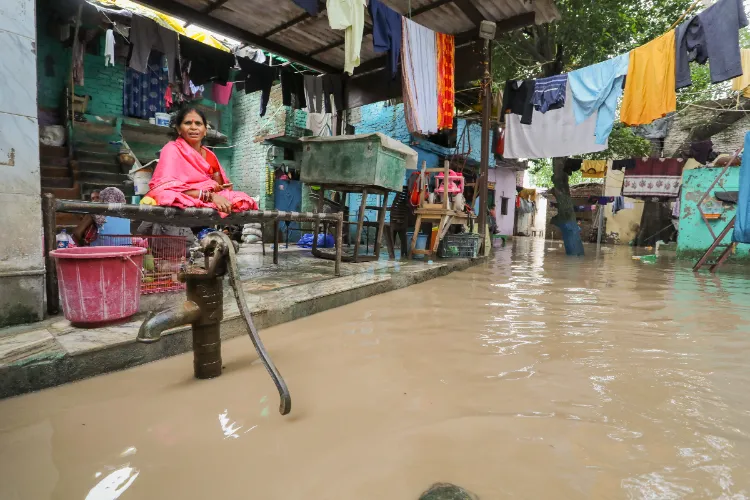 Family members in the flooded area of their house, in Nigambodh Ghat area, New Delhi