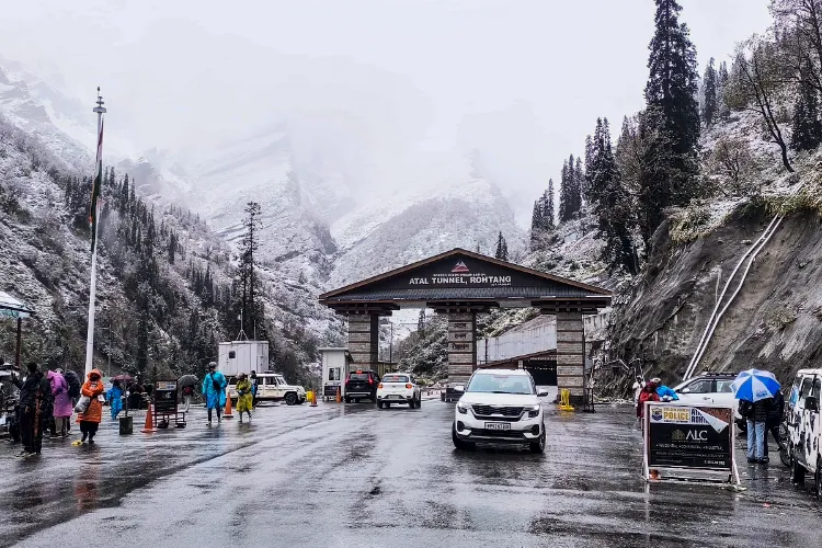 Kullu: Vehicles pass through the South Portal of Atal Tunnel while people walk by after fresh snowfall, at Rohtang, in Kullu district