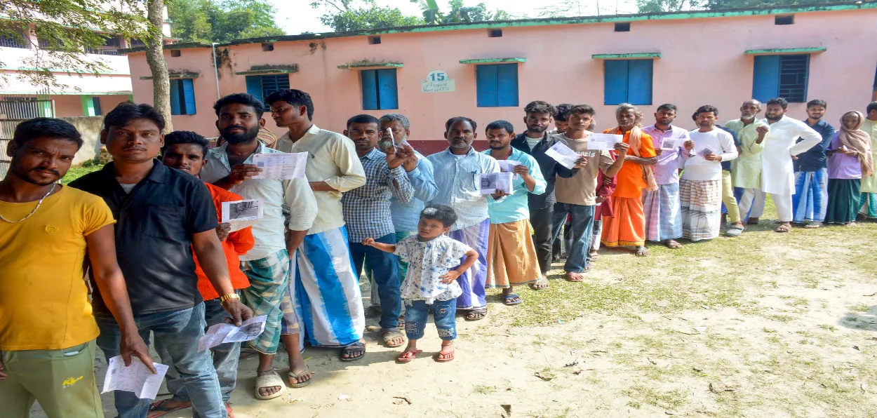 Voters wait in a queue to cast their votes at a polling booth during the second and final phase of the Bihar Assembly elections