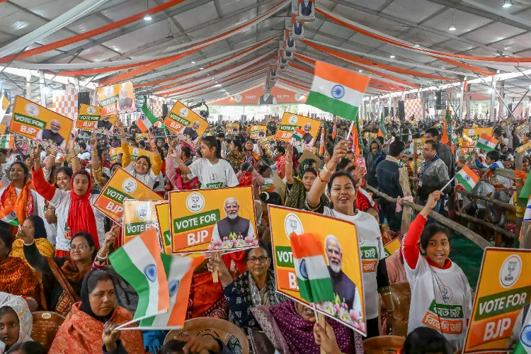 People cheer and wave flags while listening to Prime Minister Narendra Modi speaking virtually at a public meeting, in Nadia district, West Bengal