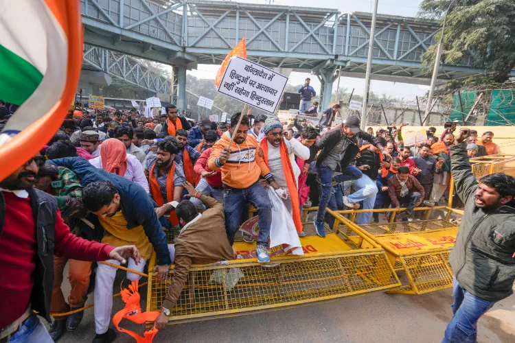 Vishwa Hindu Parishad (VHP) and Bajrang Dal members walk over barricades during a protest near the Bangladesh High Commission over attacks on Hindus in the neighbouring country, in New Delhi
