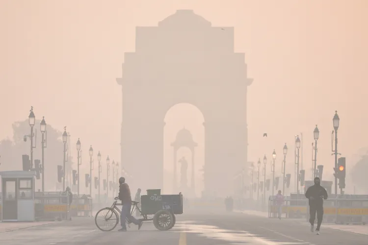 The India Gate shrouded in a layer of smog as people make their way during a cold winter morning, at Kartavya Path, in New Delhi