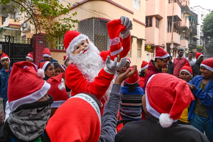 A man dressed as Santa Claus distributes chocolates among children during the Christmas celebrations, in Kolkata