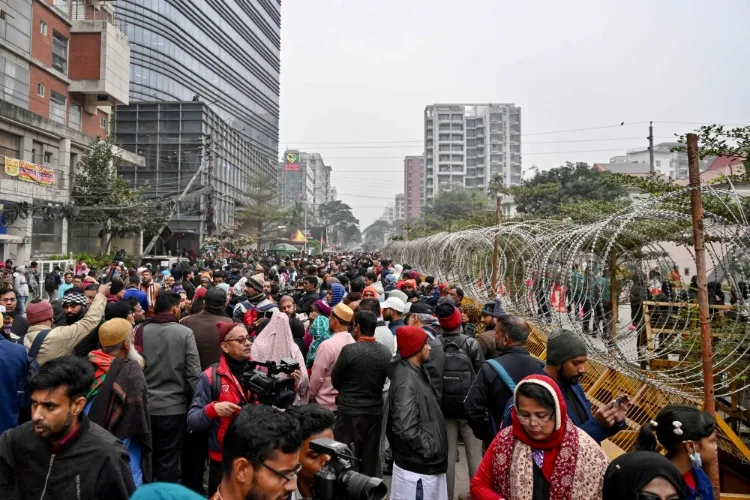 People gather behind barbed wires outside the Evercare hospital in Dhaka on December 30, 2025, following the death of Bangladesh's former prime minister Khaleda Zia at age 80