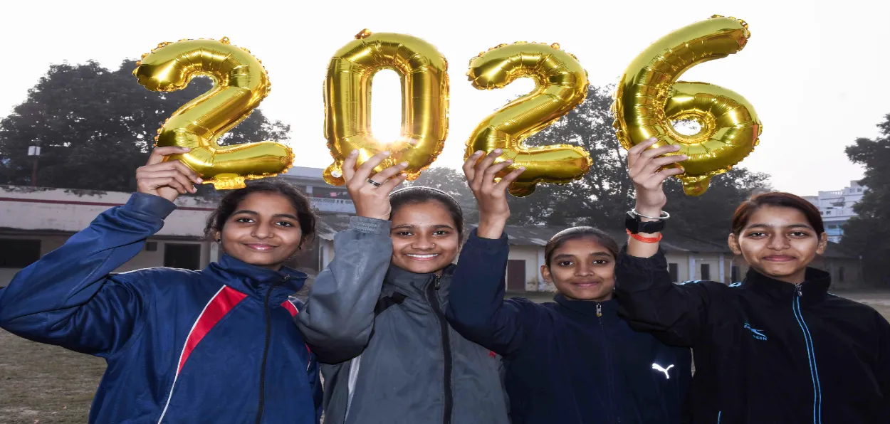 Girls with '2026' balloons pose as they celebrate the upcoming New Year 2026, in Prayagraj