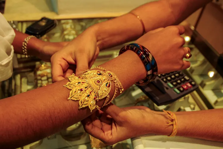  A woman tries a gold ornament at a jewellery showroom ahead of 'Dhanteras' festival, in Agartala