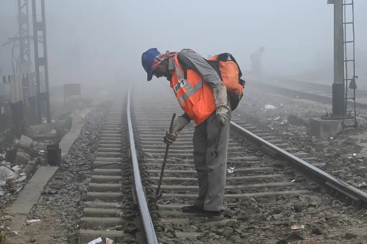 A railway employee works on tracks amid low visibility on a foggy winter morning, in Nadia, West Bengal, Friday