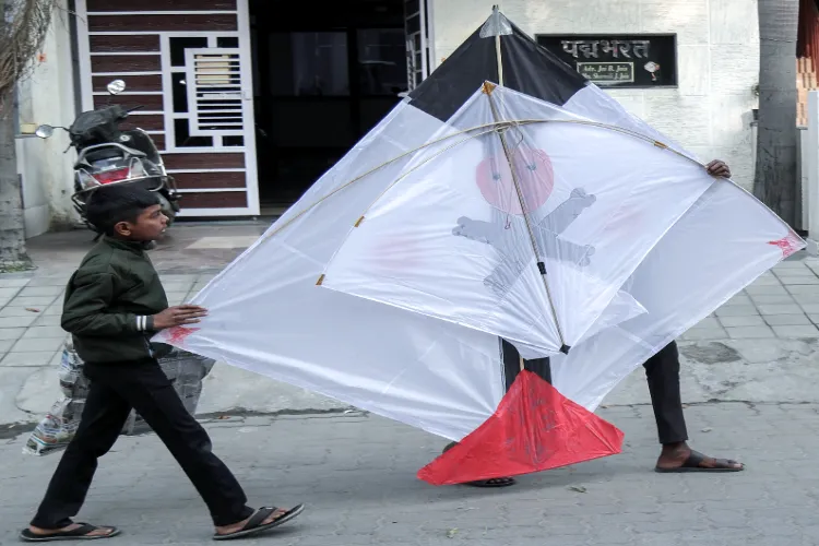 Youths carry a large kite to fly ahead of the ‘Makar Sankranti’