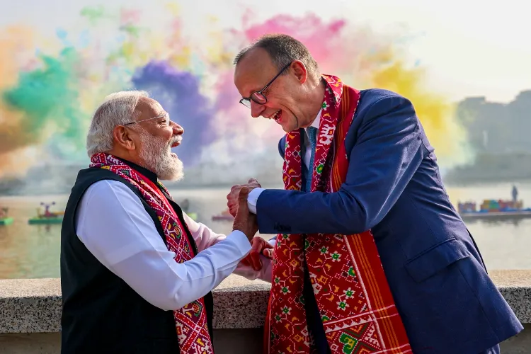 Prime Minister Narendra Modi greets German Chancellor Friedrich Merz as they share a light moment against the backdrop of colourful smoke trails released over the Sabarmati river during the International Kite Festival, in Ahmedabad