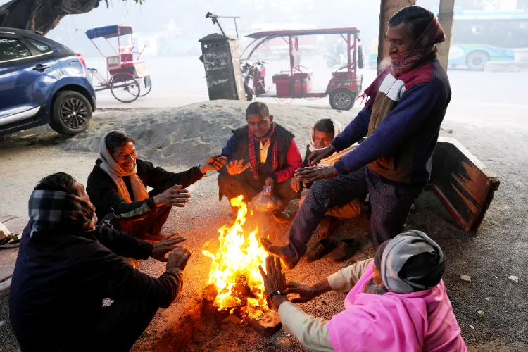  People warm themselves around a small fire as cold weather conditions prevail, in New Delhi
