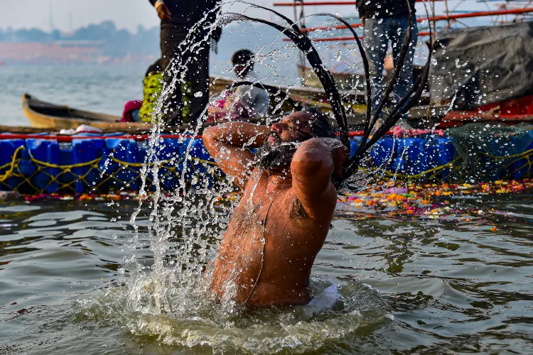 A person takes a holy dip at the Sangam on the occasion of 'Makar Sankranti' festival, during the ongoing 'Magh Mela', in Prayagraj