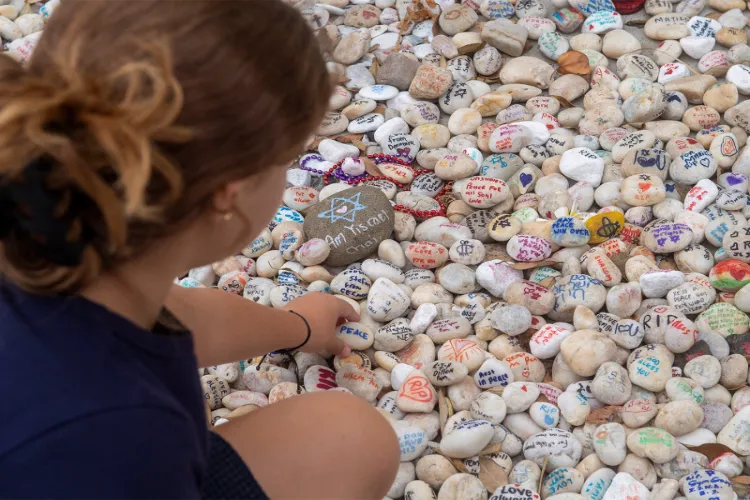 A visitor places a pebble at a memorial site in remembrance to the lives lost during the Bondi Beach mass shooting on December 14, 2025