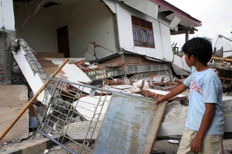 A boy looks at a damaged house rocked by earthquakes, in Solok, West Sumatra province March 6, 2007. 