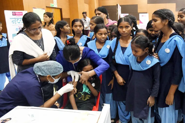 A health worker inoculates the HPV vaccines to a school girl during a free HPV vaccination camp 