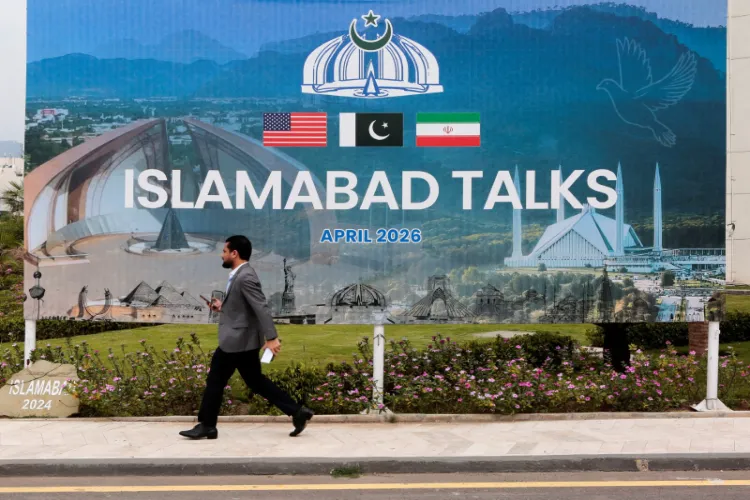 A passerby walks by a billboard near the media centre in Islamabad, where delegations from the United States and Iran are set to engage in peace talks.