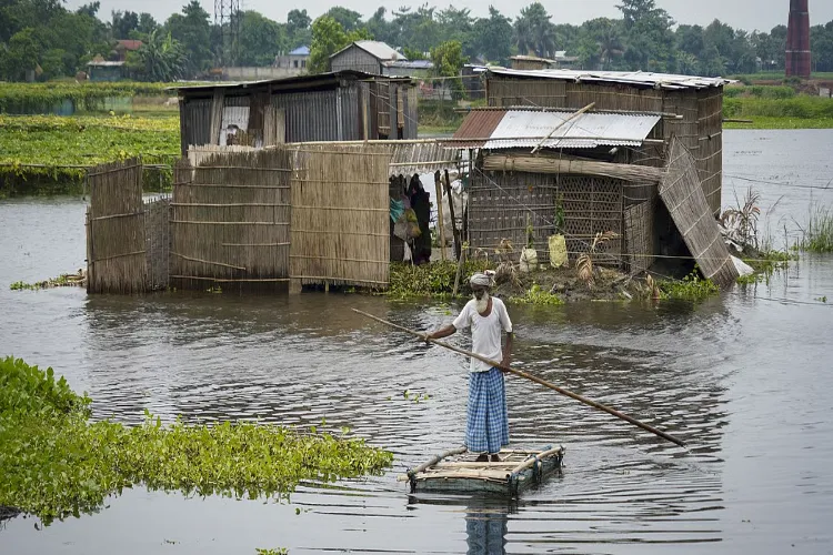 Morigaon: A man uses a makeshift raft to travel through floodwaters, in Morigaon district, Assam