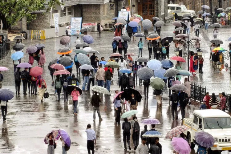 People cover themselves with umbrellas as they walk amid rainfall 
