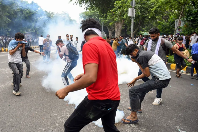 Protestors cover their face as security personnel fire tear gas shells on them during their protest march towards Parliament