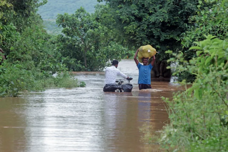 People wade through a flood water of the Mahanadi river entered the villages below Cuttack and Banki districts in Odisha 