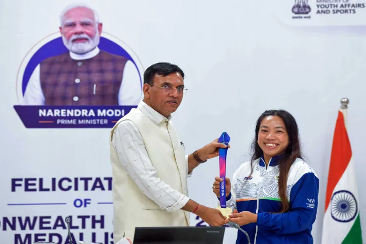 Mansukh Mandaviya felicitating women's 48kg gold medallist Mirabai Chanu during a ceremony honouring the weightlifting contingent for its performance at CWG 2026 