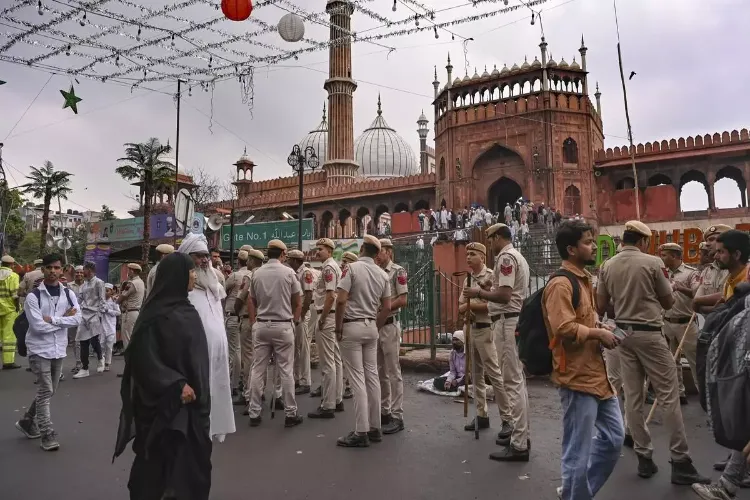 Police personnel stand guard as people arrive to offer prayers at Jama Masjid ahead of the Eid Al-Fitr festival celebrations, in New Delh