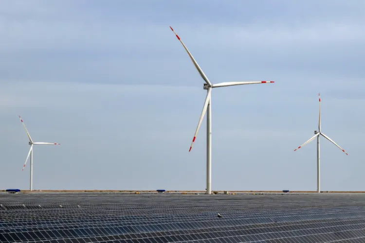 A vast solar power array with wind turbines at a renewable energy facility.