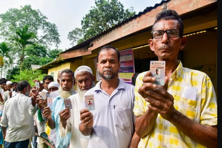 Voters display their voter identity cards as they stand in a queue to cast their votes at a polling booth during the Nagaon Lok Sabha constituency by-election, in Morigaon district, Assam