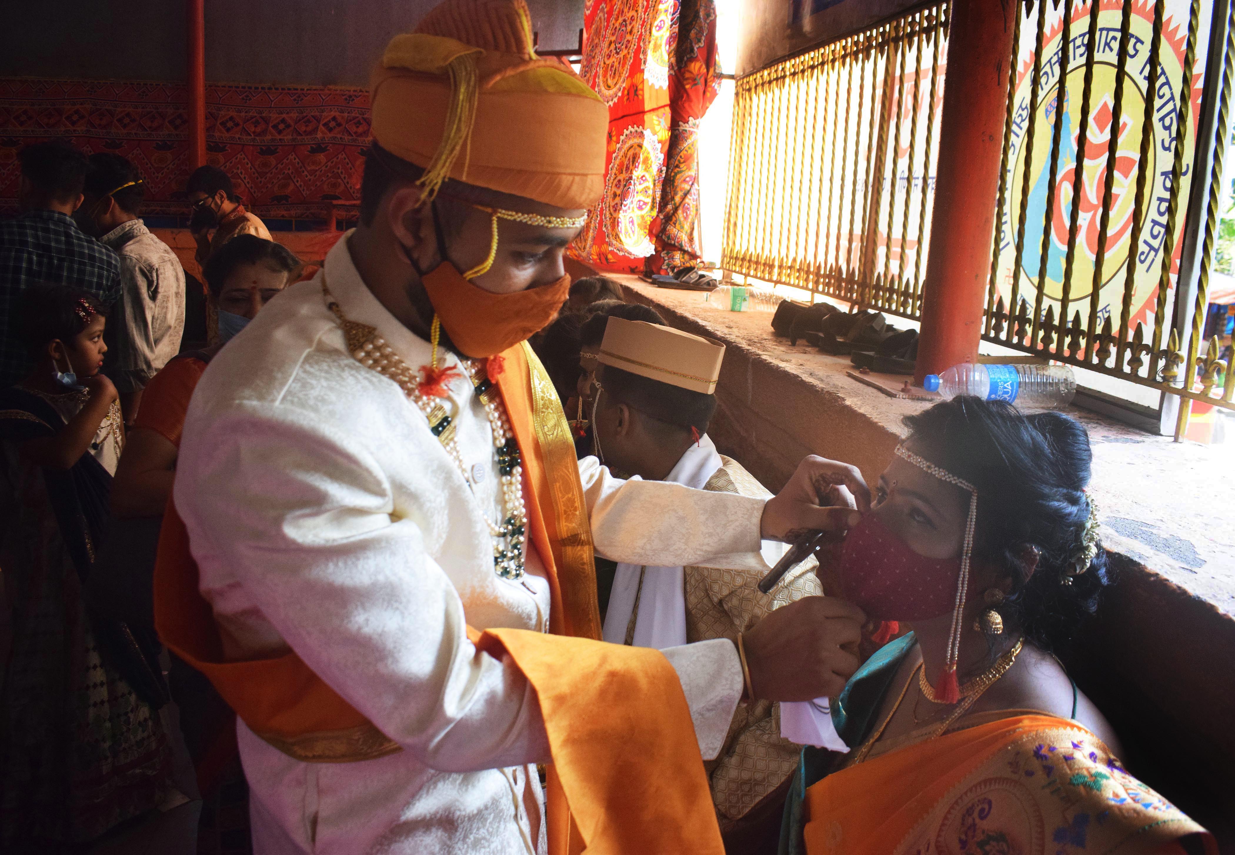 A groom adjusts the mask of his bride during their wedding in Mumbai, Maharashtra