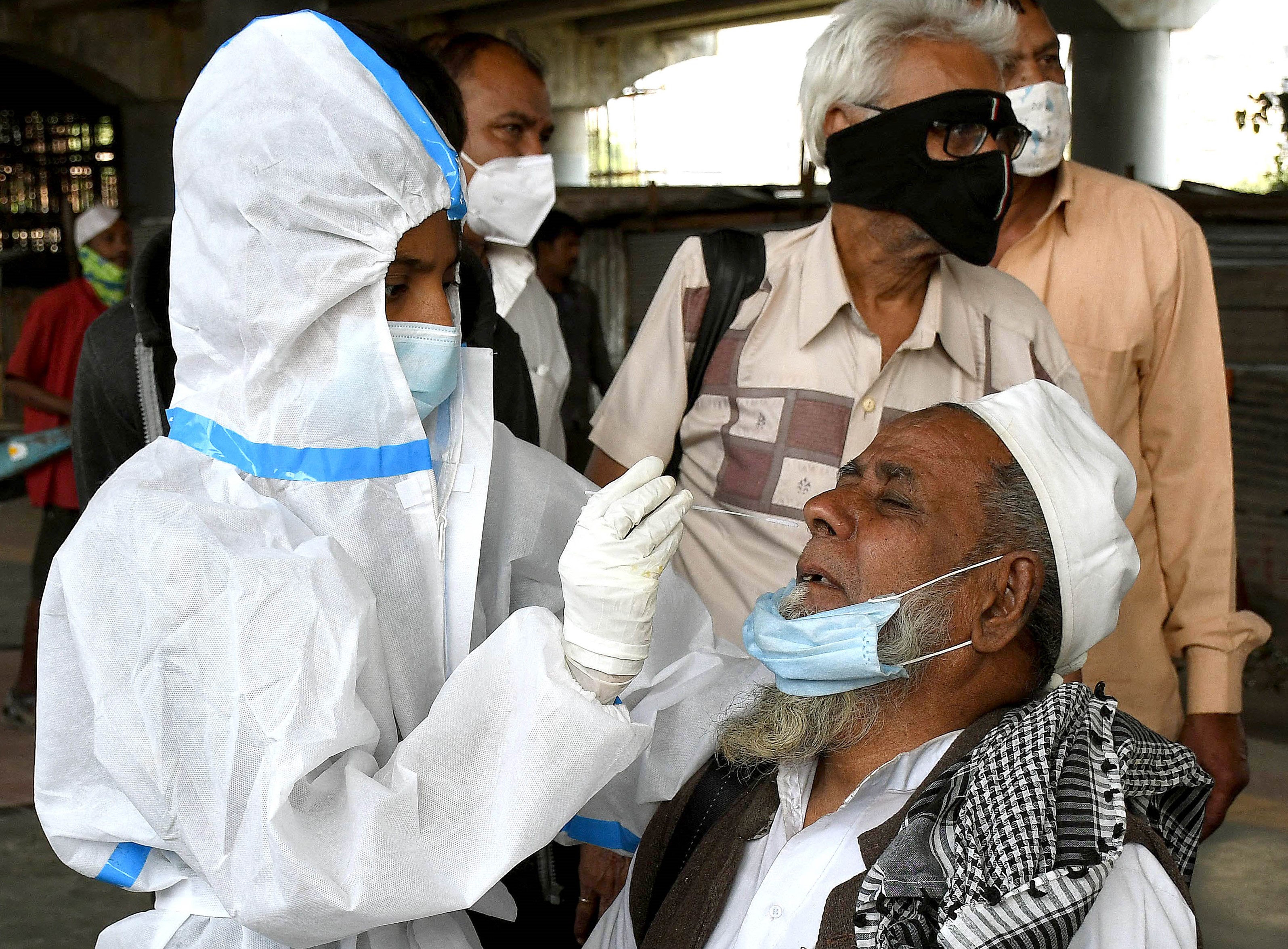 A health worker wearing PPE kit collects swab sample of an old man on his arrival for the COVID-19 test, in Mumbai