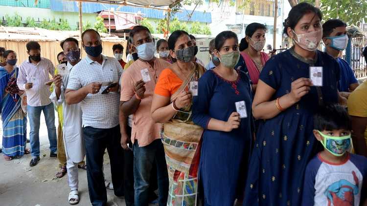 People stand in a queue at a polling station to cast their vote